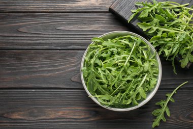 Taze yeşil roka yaprakları koyu ahşap masada, düz yerde. Metin için boşluk