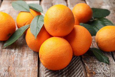 Taze portakallar ve yapraklar ahşap masada, yakın plan.