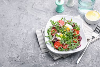 Lezzetli roka salatası, sebzeler ve yumurta gri masada servis ediliyor. Metin için boşluk