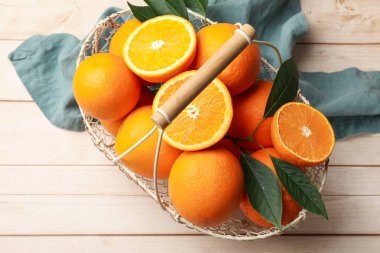 Taze portakallar ve yapraklar sepetin içinde açık ahşap masa, üst manzara