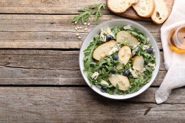 Lezzetli salata roka, armut, mavi peynir, fıstık ve yaban mersinli ahşap masa, düz yatak. Metin için boşluk