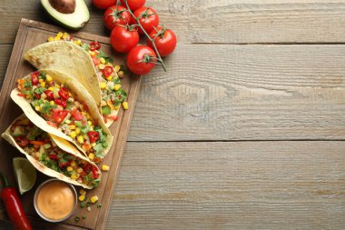 Tahta masada servis edilen nohut, mısır ve kinoalı lezzetli vejetaryen tacolar. Metin için boşluk