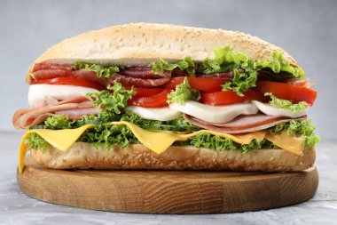 Jambonlu, peynirli ve sebzeli baget sandviç. Gri dokulu masa, yakın plan.