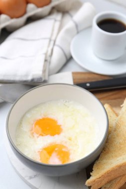 Kâsede yarı haşlanmış yumurta, kahve ve beyaz fayanslı masada kızarmış ekmek, yakın plan. Geleneksel Asya kahvaltısı