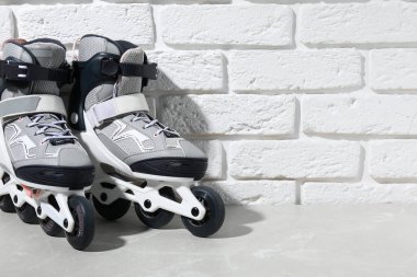 Beyaz tuğla duvarın yanındaki gri mermer masada patenler, yakın plan. Metin için boşluk