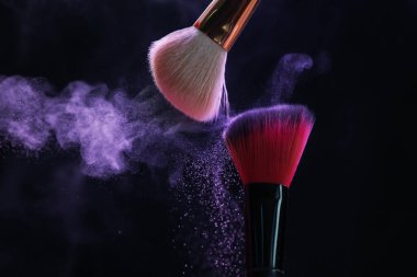 Siyah arka planda neon ışıklarda mor göz farlı makyaj fırçaları, yakın plan