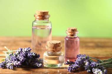 Ahşap masada lavanta şişeleri ve çiçekler, yakın plan.