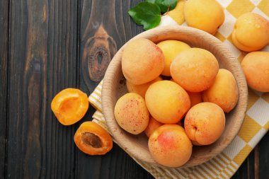 Taze ıslak kayısılar kasede, koyu ahşap masada, düz yatıyordu.