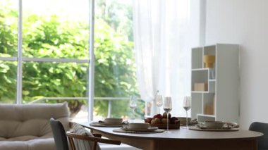 Yemek odasında güzel bir masa, sandalye ve dekor var. Kamera aşağı iniyor