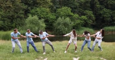 Takım oluşturma. Dışarıda halatla çekme oyunu oynayan bir grup mutlu insan.