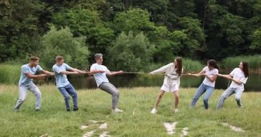 Takım oluşturma. Dışarıda halatla çekme oyunu oynayan bir grup mutlu insan.