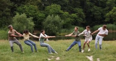 Takım oluşturma. Dışarıda halatla çekme oyunu oynayan bir grup mutlu insan.