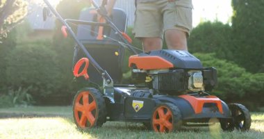 Lviv, Ukrayna - 2 Temmuz 2025: Bahçedeki çim biçme makinesine çim biçme makinesi takan adam, yakın plan