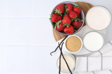 Panna cotta için farklı malzemeler. Süt, şeker, vanilya ve çilek beyaz fayanslı masa, düz yatak. Metin için boşluk