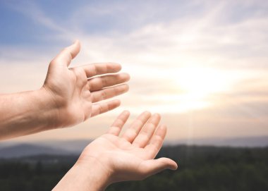 Umut. Gökyüzüne karşı el ele tutuşan adam bulutlar ve dağlarda güneş, yakın çekim