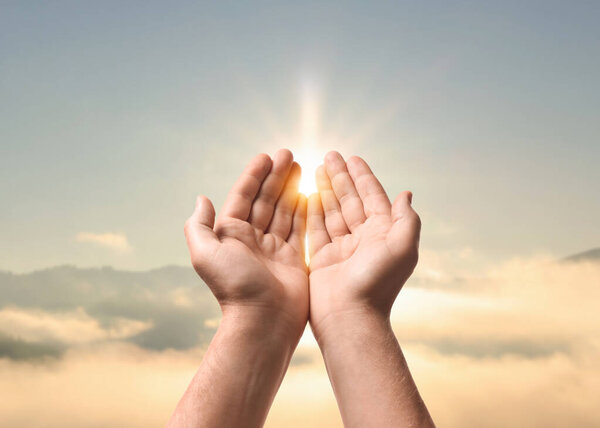 Надежда. Человек держит руки на небе с ярким солнцем в горах, крупным планом