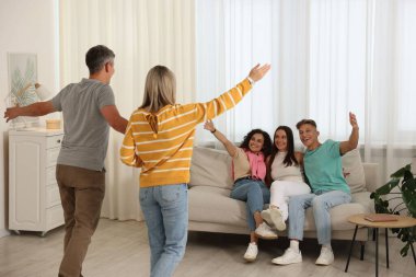 Mutlu arkadaşlar evdeki kanepede çiftleri selamlıyor.