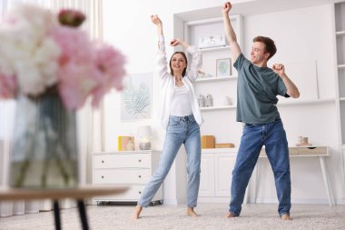 Mutlu genç çift evde dans ediyor, düşük açılı.