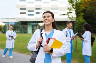 Dışarıda defterleri olan üniformalı bir tıp öğrencisi. Seçici bir odak noktası.