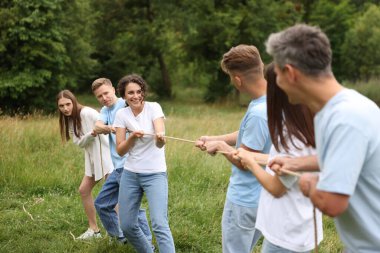 Takım oluşturma. Dışarıda halatla çekme oyunu oynayan bir grup mutlu insan.