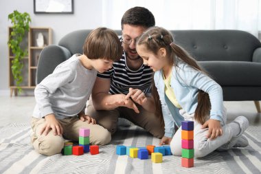 Babam ve çocukları evde renkli küplerle oynuyorlar.