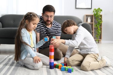 Babam ve çocukları evde renkli küplerle oynuyorlar.