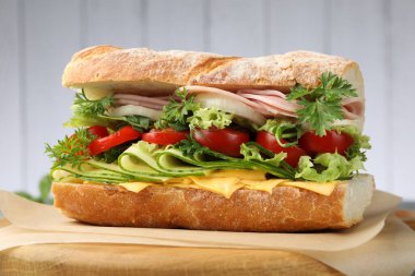 Jambonlu, peynirli ve sebzeli baget sandviç. Arka planda bulanık gri, yakın plan.