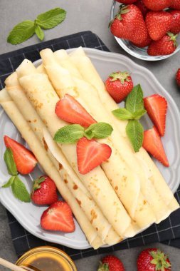 Çilekli leziz krepler ve gri masada nane şekeri.