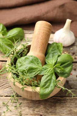 Kabuklu havan, farklı aromatik otlar ve baharatlar ahşap masada, yakın plan.