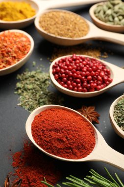 Siyah masada kaşıklardaki farklı aromatik baharatlar, yakın plan.