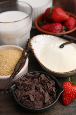 Panna cotta için farklı malzemeler. Süt, şeker, vanilya, çikolata ve çilek ahşap masada, yakın plan.