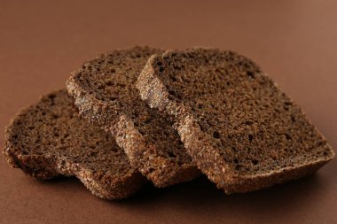 Kahverengi arka planda taze çavdar ekmeği parçaları, yakın plan.