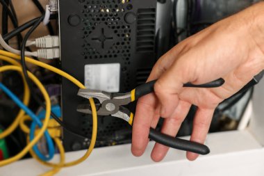 İçerde penseyle ısıtma kaloriferini tamir eden adam, yakın plan.