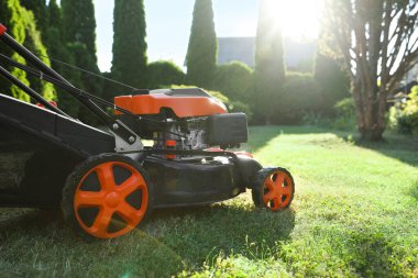 Bahçedeki yeşil çimlerin üzerinde bir çim biçme makinesi, yakın plan. Metin için boşluk