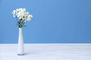 Beyaz ahşap masadaki vazodaki güzel çiçekler açık mavi arkaplan, metin için alan