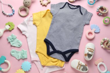 Pembe arka planda bebek kıyafetleri ve aksesuarlar, düz yatış.