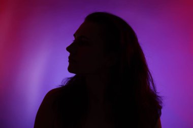 Renkli arka planda neon ışıklarla poz veren kadın silueti