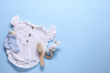 Açık mavi arka planda bebek kıyafetleri ve aksesuarlar, düz yatış. Metin için boşluk