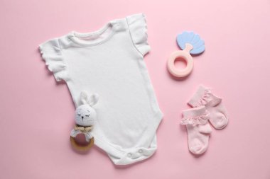 Pembe arka planda bebek kıyafetleri ve aksesuarlar, düz yatış.