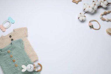 Sevimli bebek kıyafetleri, aksesuarlar ve beyaz arka planda pamuk çiçekleri, düz yatış. Metin için boşluk