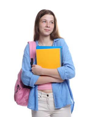 Sırt çantası ve beyaz arka planda defterleri olan genç bir kız.