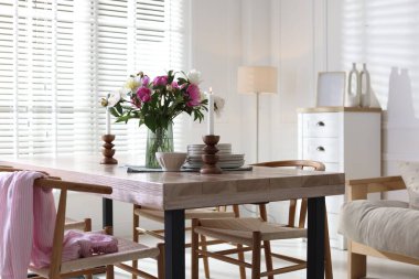 Odada güzel çiçekler ve bulaşık takımı olan yemek masası. İç tasarım