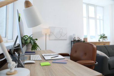 Ofisteki ahşap masada modern bilgisayar ve kırtasiye malzemeleri, yakın çekim. Rahat bir iş yeri