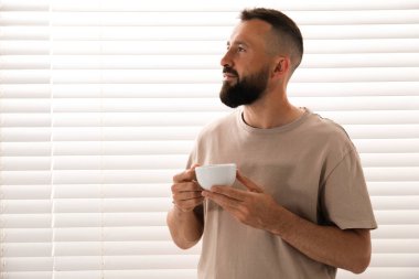 Uyum. Evinin penceresinin yanında bir bardak içkisi olan adam.