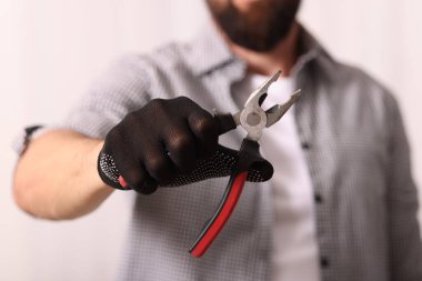 Eldivenli bir adam penseyi içeride tutuyor, yakın plan.