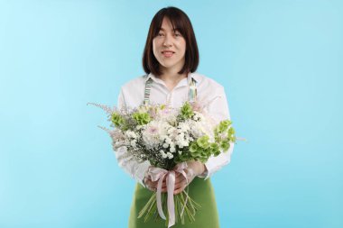 Açık mavi arka planda güzel bir buket çiçekle çiçekçi.