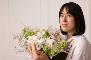 Beyaz duvarın yanında güzel çiçek buketi olan bir çiçekçi.