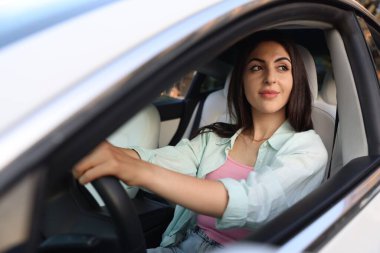 Araba kullanırken direksiyon tutan kadın, dışarıdan görüyor