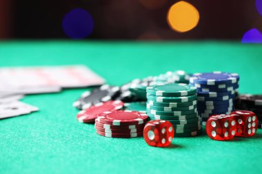 Kumarhane fişleri ve zarlar yeşil masada bulanık ışıklara karşı, yakın plan. Metin için boşluk