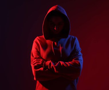 Anonimlik. Yüzünü koyu kırmızı arka planda saklayan kadın.